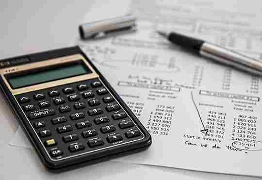 Une calculatrice, un crayon et une feuille avec des chiffres pour illustrer le budget.