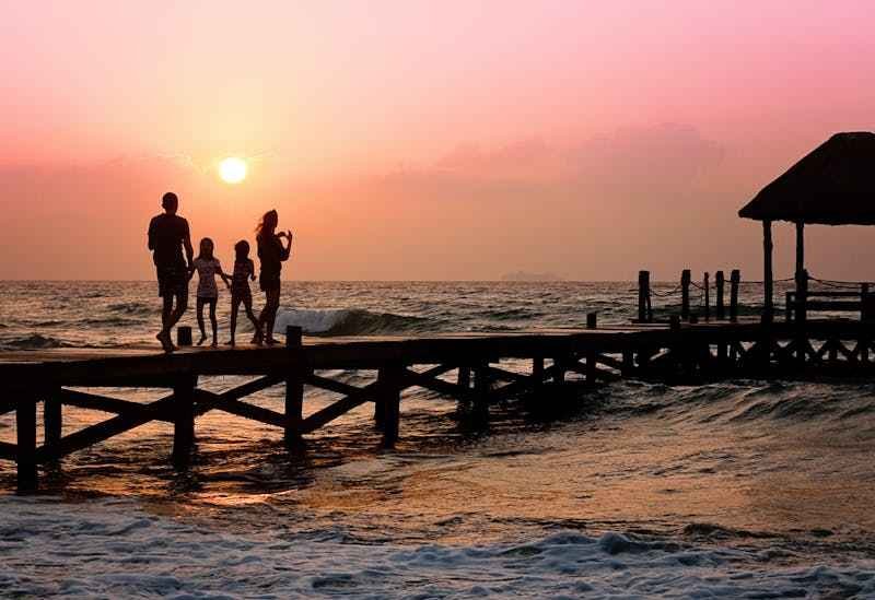 Une famille se promène le soir sur un ponton, en front de mer, en Guadeloupe.