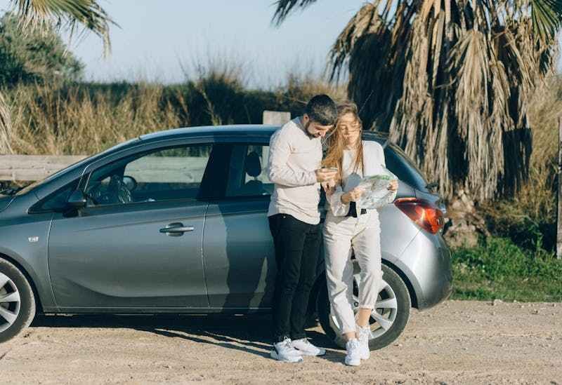 Un couple est devant une voiture de location, lis une carte routière, pour explorer les environs.