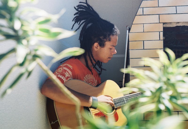 un jeune joue de la guitare, et joue de la musique des Antillais.