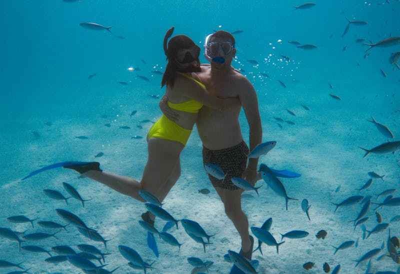 Un couple fait du snorkeling au milieu des poissons.