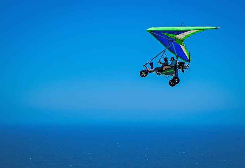 2 personnes font de l'ULM sous un ciel bleu azur.